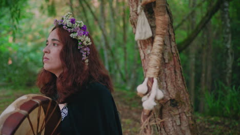 druid girl in a forest playing a shamanic drum medium close shot