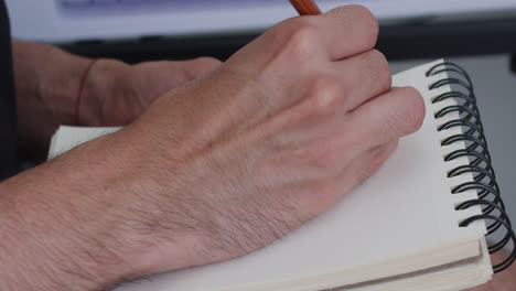 beautiful close up slow motion shot of a young man's hands writing and jotting down data with a pencil in a notebook