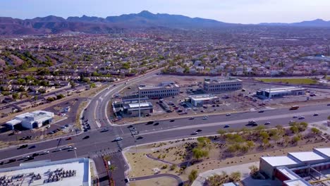 Aerial-pan-of-traffic-intersection,-commercial-complex-and-surrounding-neighborhoods-with-mountains