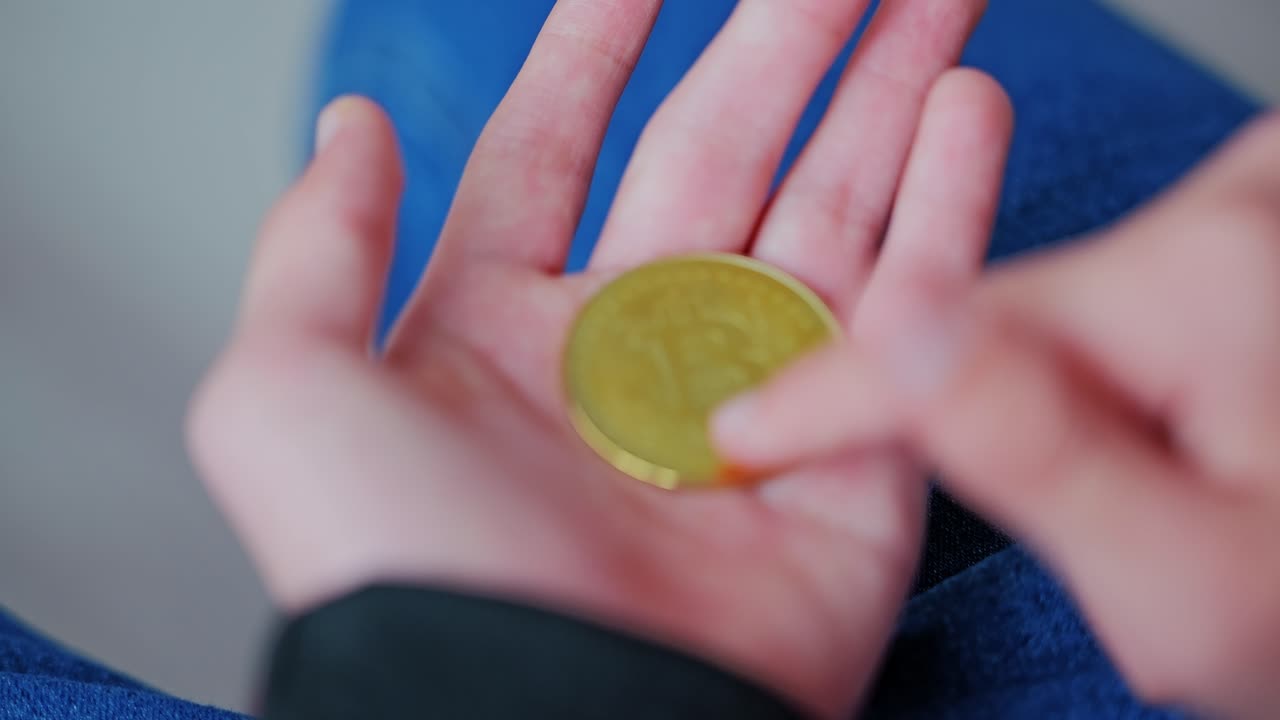 Handling of gold BTC coin reflects curiosity in cryptocurrency trend, Young boy