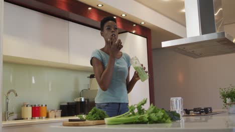 smiling african american attractive woman tasting homemade smoothie in kitchen