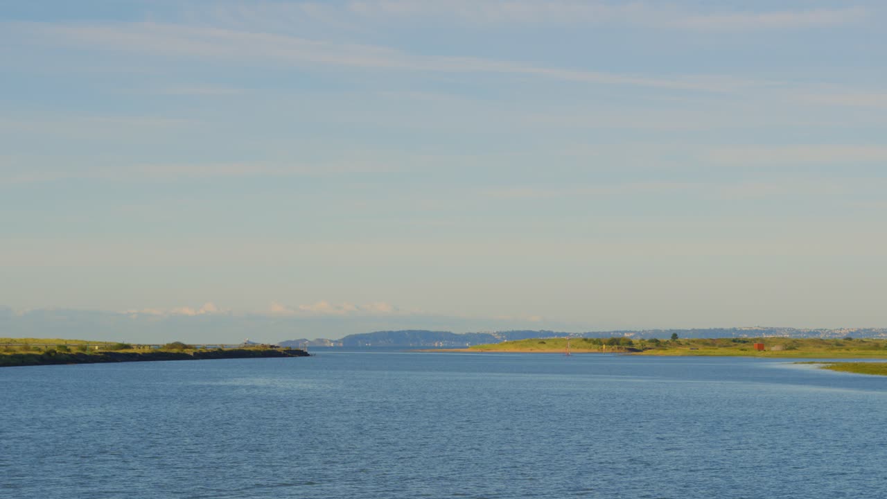 River Neath at High Tide with Beautiful Calm Blue Water and Green Surrounding Wetlands with Mumbles in Swansea in Distance