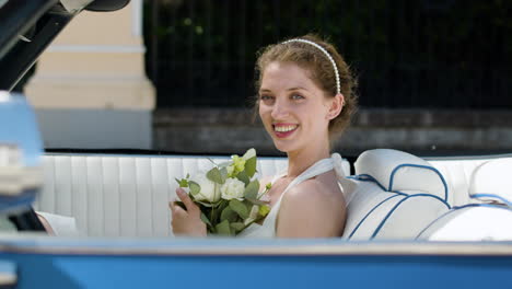 Side-view-of-bride-sitting-on-blue-convertible-car
