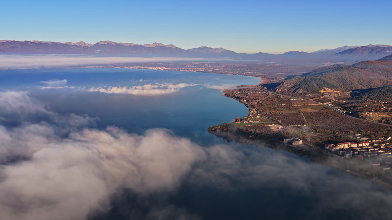 Aerial drone view of a Galichica mountain ridge rising above a sea of clouds, with soft layers of fog covering the valley below