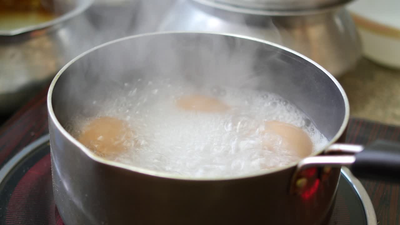 Boiling eggs in hot water in a cooking pan ,