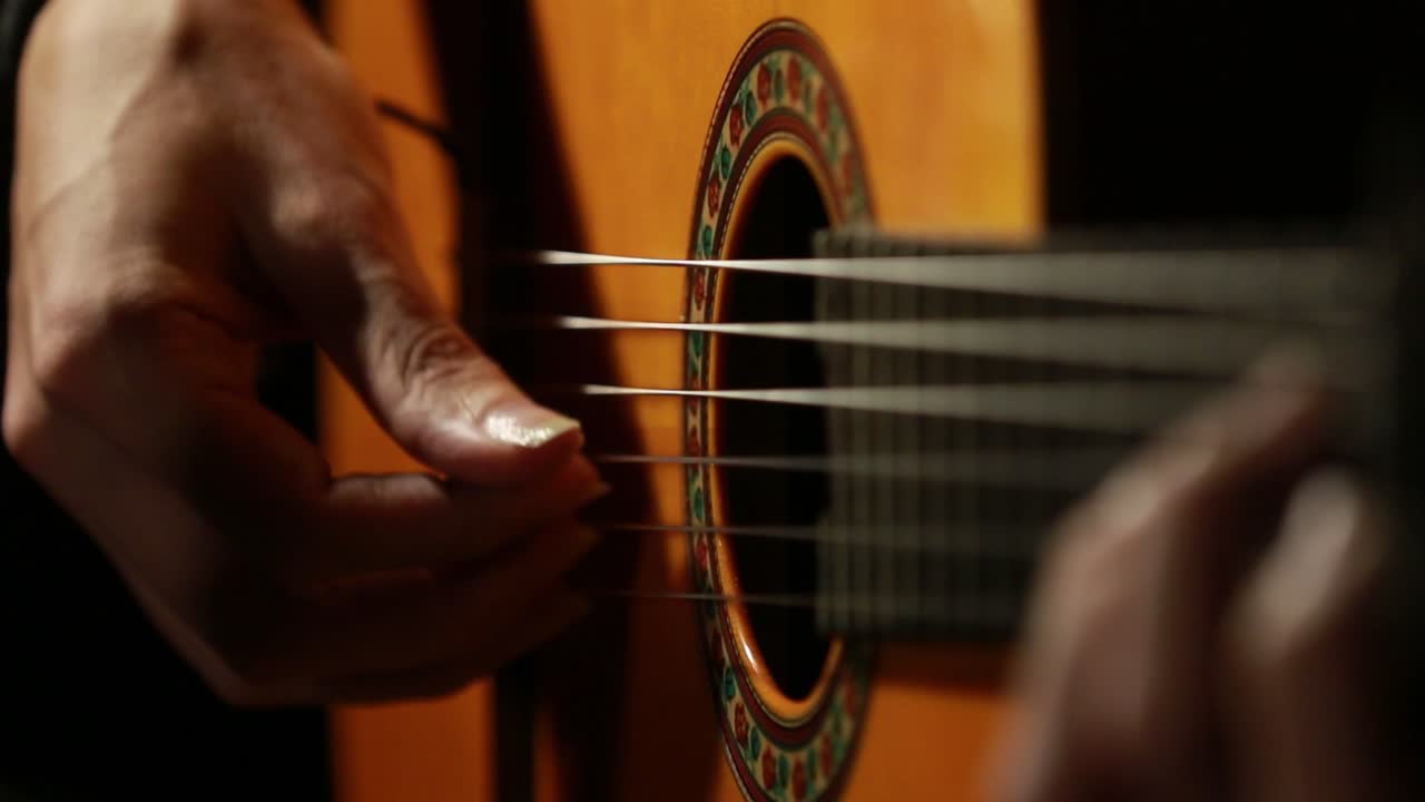 primer plano de las manos del hombre tocando una guitarra clásica