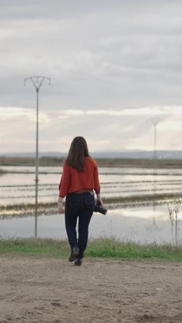woman walking with camera in rural landscape