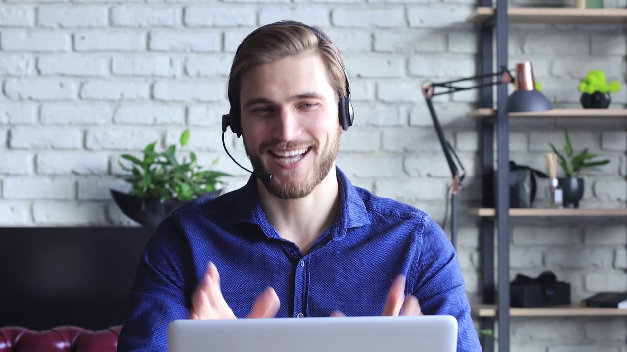 Giovane uomo sorridente con cuffie che parla in videochiamata