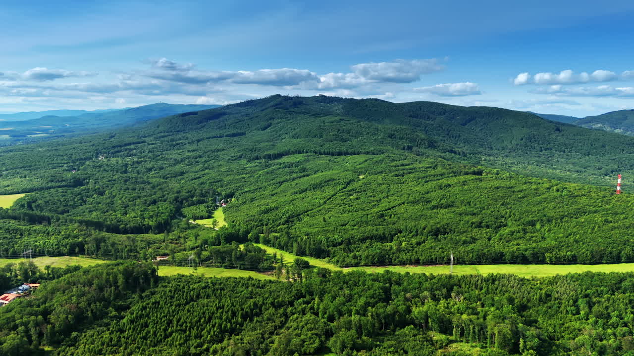 Spectacular mountains covered with green forests. Electrical transmission line crosses the landscape. Aerial perspective.