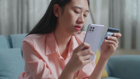 close up of asian woman holding credit card and smartphone shaking his head due to unable pay money