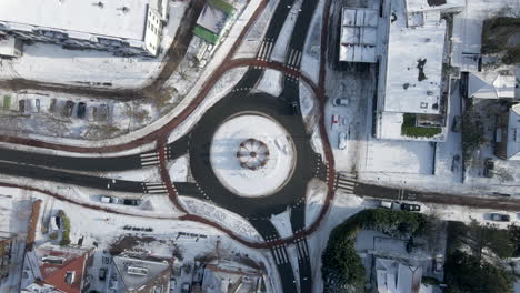 top down aerial of traffic using roundabout in winter - drone lifting up