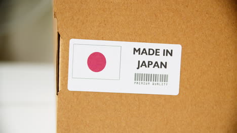 hands applying made in japan flag label on a shipping cardboard box with products