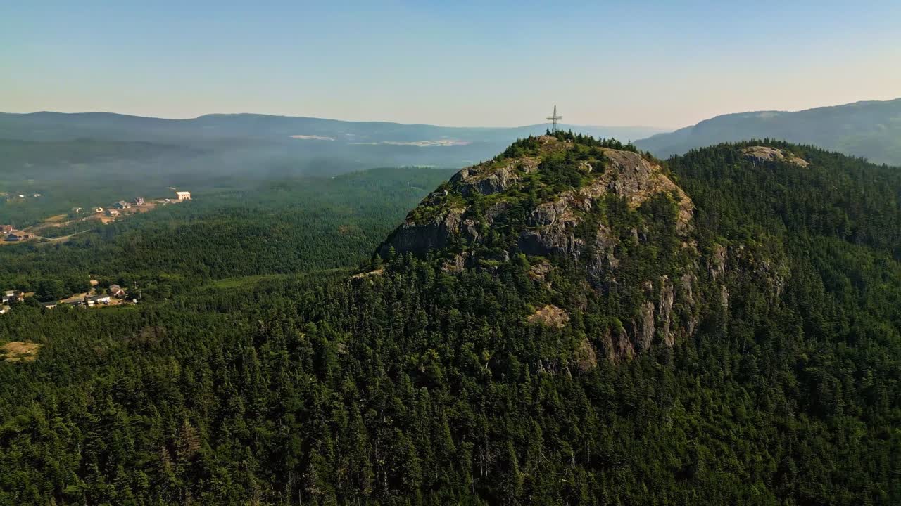 A drone sweeps over Holyrood's scenic hills, capturing smoke drifting above rocky slopes and the coastal town near Conception Bay on Newfoundland’s east coast