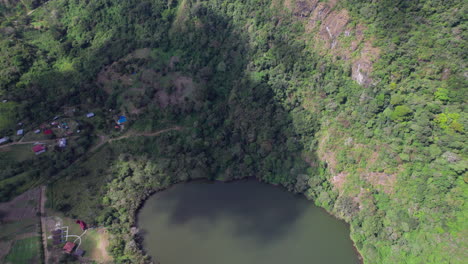 Un-Lago-Apartado-Rodeado-De-Exuberante-Vegetación-Y-Una-Pequeña-Comunidad,-Vista-Aérea