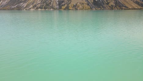 cara empinada y rocosa de una montaña a orillas del lago tekapo, nueva zelanda