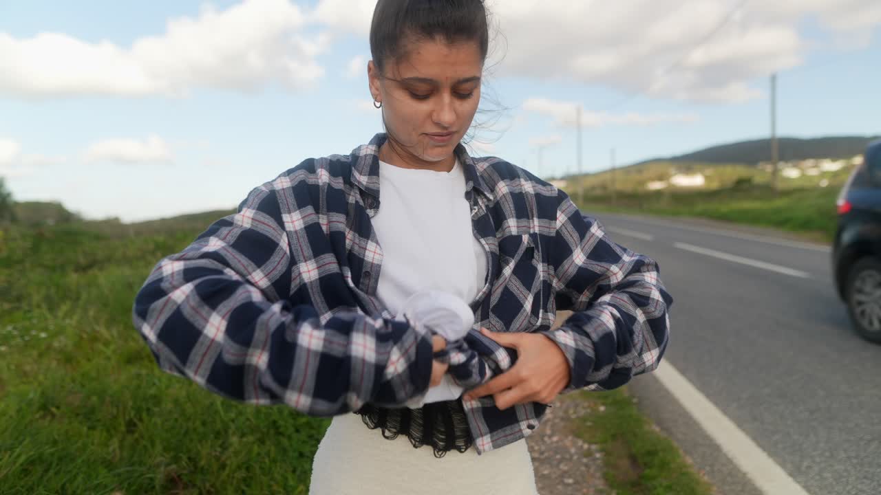 mujer ajustando camisa a cuadros por la carretera