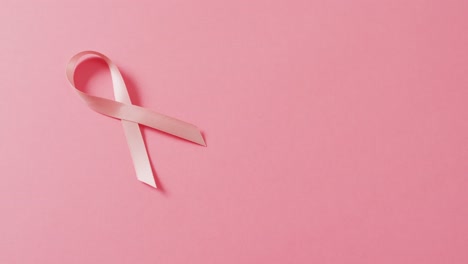 video of pink breast cancer ribbon on pale pink background