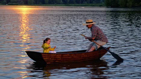 father and daughter rowing a boat at sunset