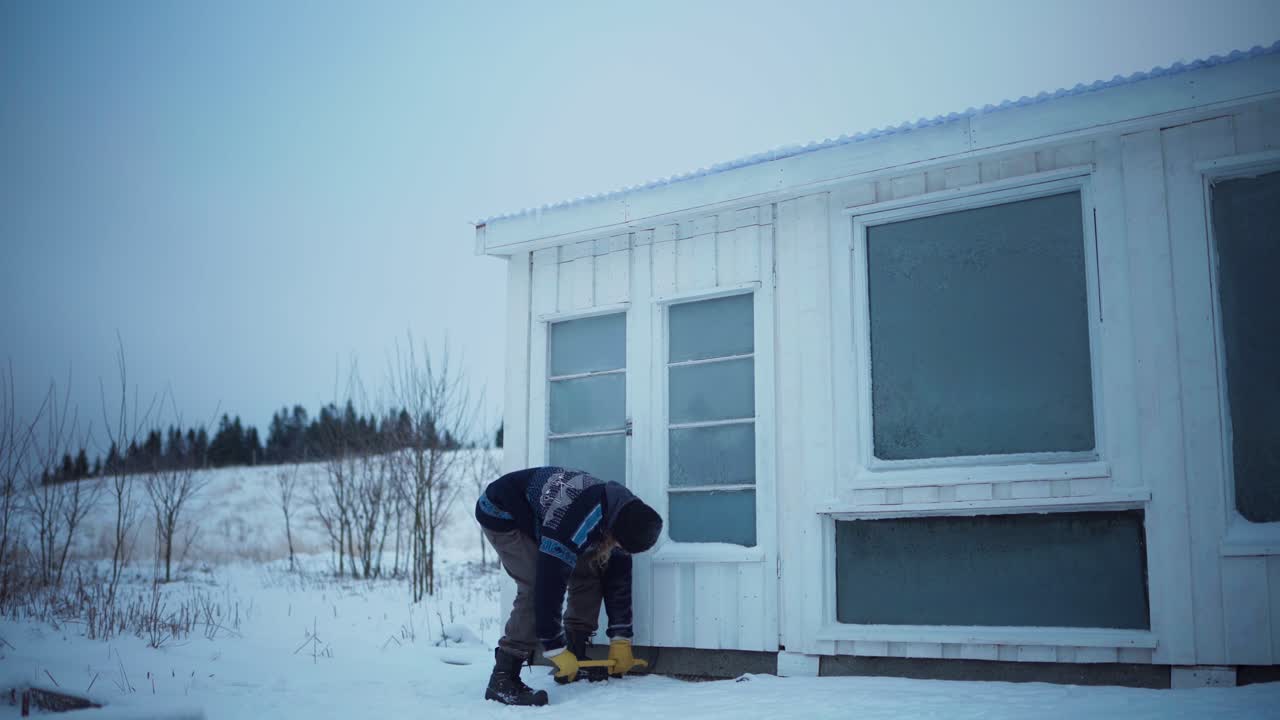 크로바를 가진 남자는 나무 팔레트 벽을 당기려고합니다