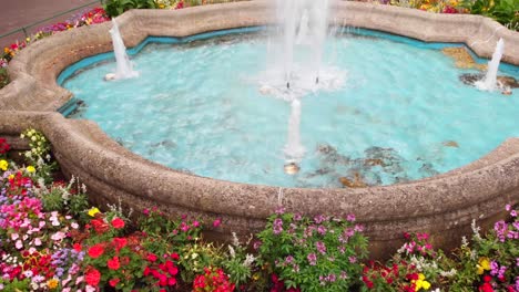 a drone rises over a small beautiful fountain in the center of the park