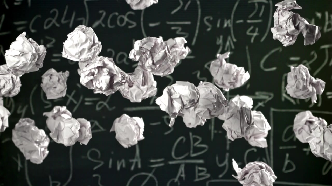 Crumpled Paper Balls Falling Against a Chalkboard with Math Equations