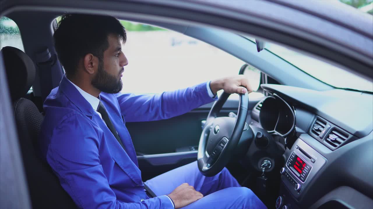 Man in blue suit driving a car
