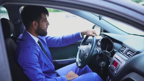man in blue suit driving a car