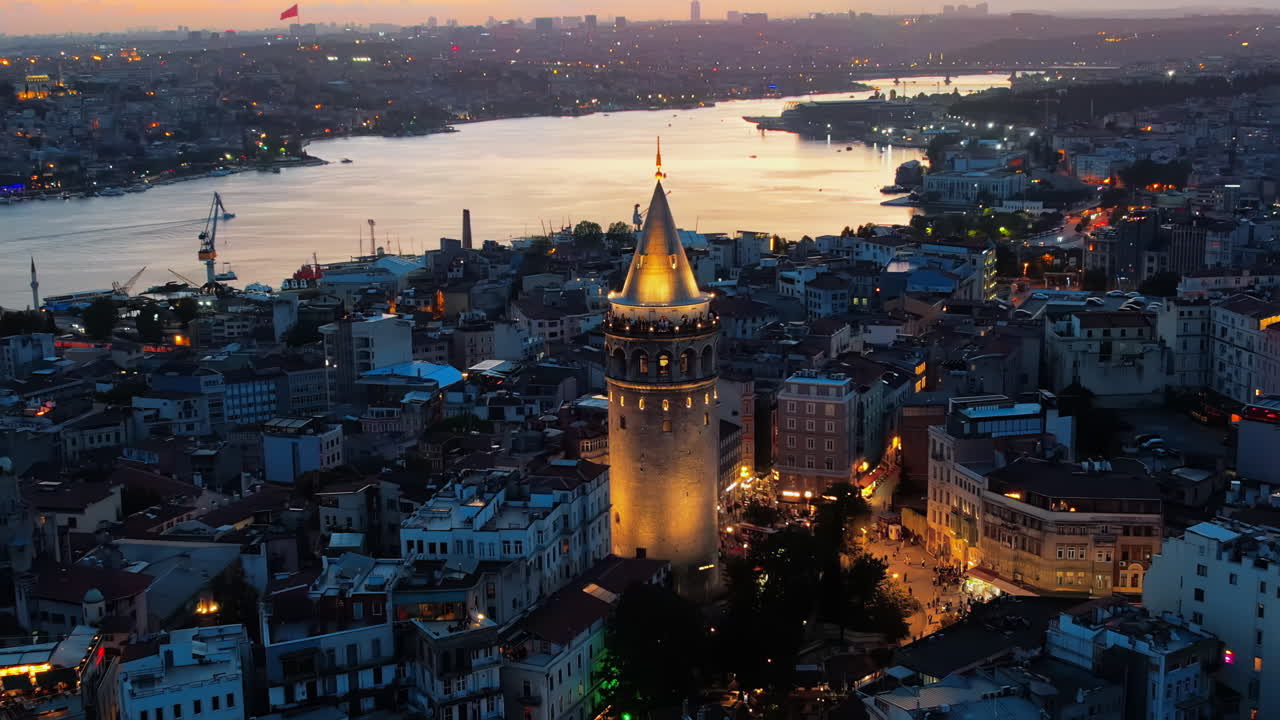 Aerial drone view of Istanbul at sunset, Turkey. Multiple residential buildings around the Galata tower, nightlights, Golden Horn waterway on the background