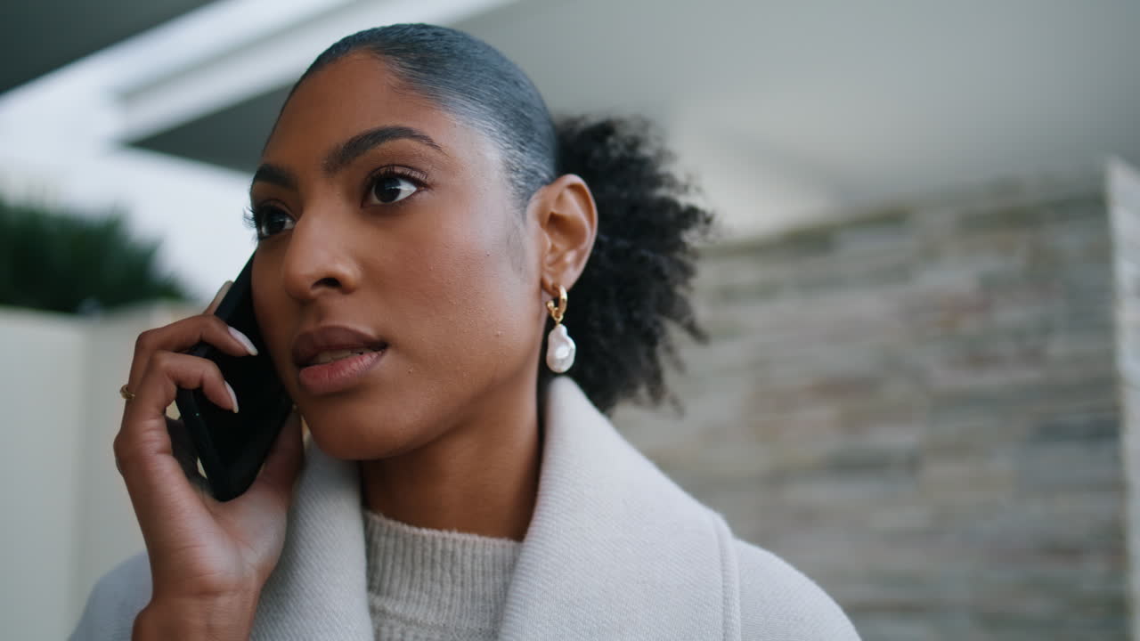 Attractive woman speaking smartphone on street closeup. Serious african american