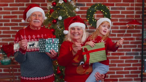 Feliz-Pareja-De-Ancianos-Abuelos-Con-Nieta-Sosteniendo-Luces-De-Navidad-De-Bengala-Encendidas-Bengalas