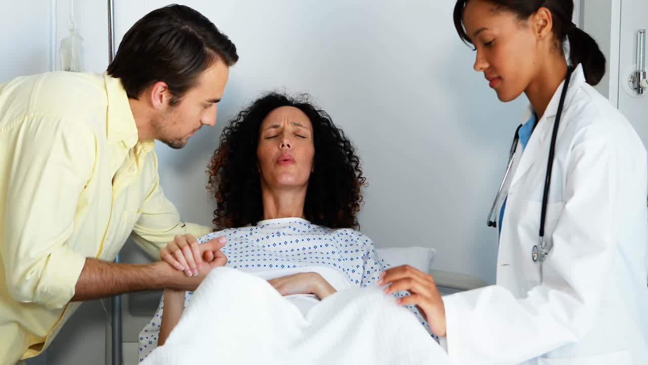 Medico e uomo che conforta donna incinta in reparto