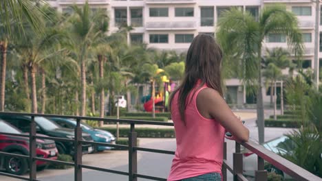 lady with long hair stands by metal fence and chats