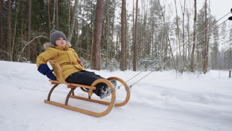 portrait of a smiling boy 3-4 years old in slow motion who rides a sled in a snowy forest in winter