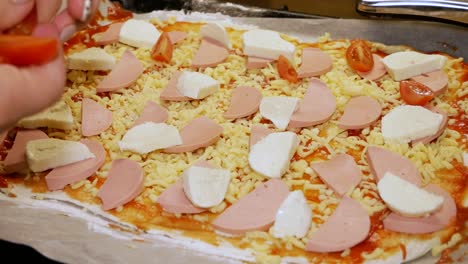 la cocinera casera está poniendo tomates frescos en pizza casera
