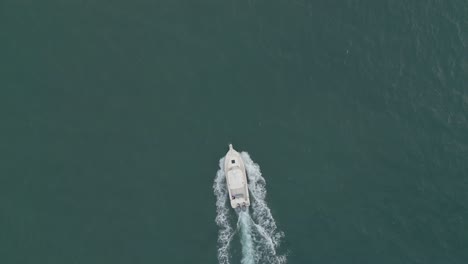 Dron-De-Disparo-Aéreo-Que-Sigue-A-Un-Pequeño-Bote-Que-Acelera-En-El-Océano-Vista-De-Pájaro-De-Arriba-Hacia-Abajo