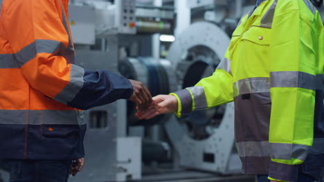 businesspeople shaking hands at machinery plant. cheerful team work concept.