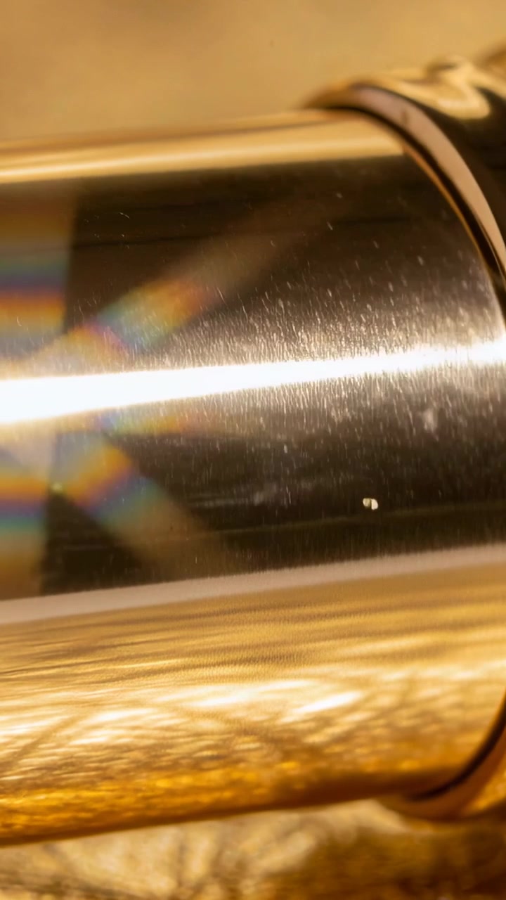 Video verticale: Luce che si sposta muovendo un cilindro di metallo su una superficie calda del tavolo, rivelando finiture e un prisma.