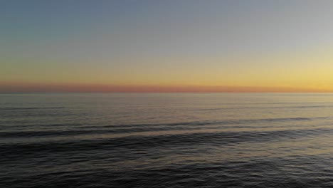 Cinematic-aerial-drone-flying-over-ocean-waves-during-beautiful-sunset