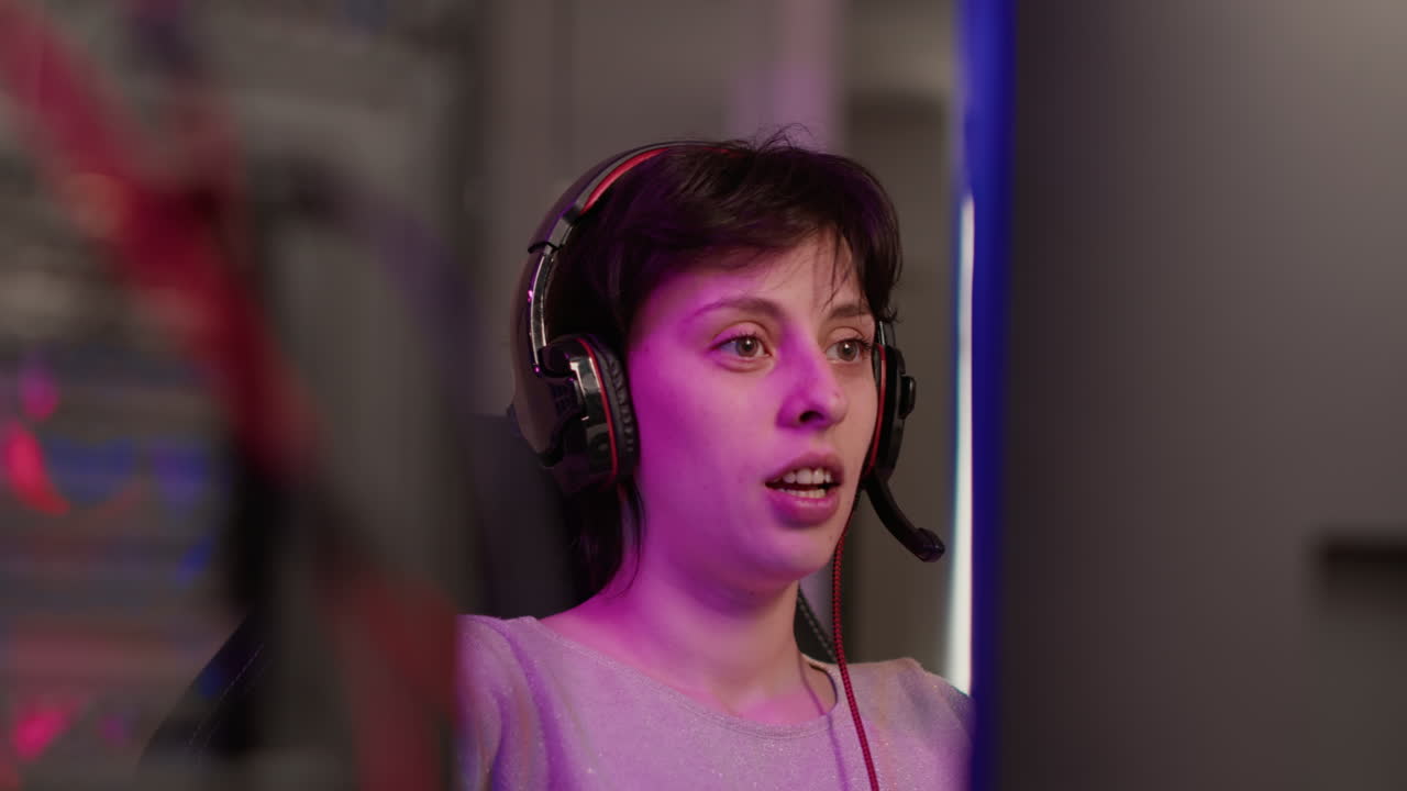 Handheld shot of gamer girl talking on headset while explaining gameplay to subscribers