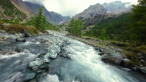 fpv racing drone flying over val ventina water rapids surface at low altitude