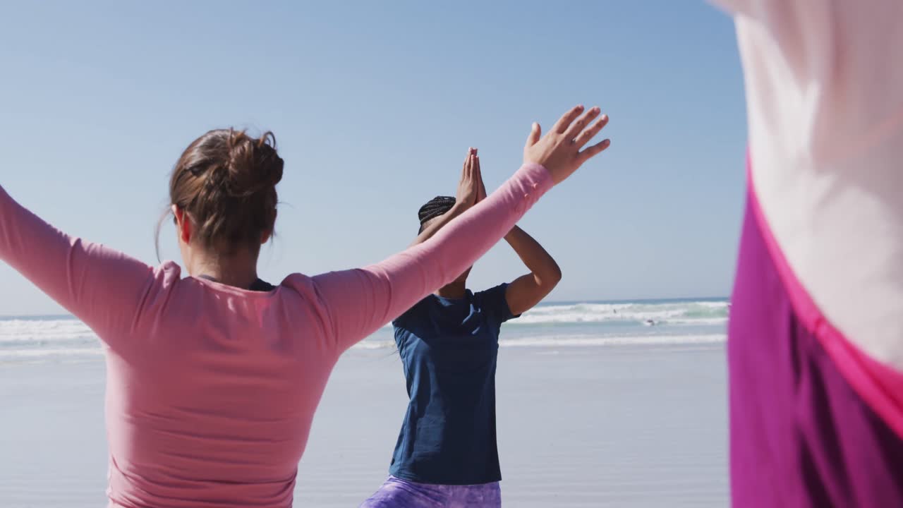 해변과 파란 하늘 배경에서 요가 자세를 취하는 다민족 여성 그룹