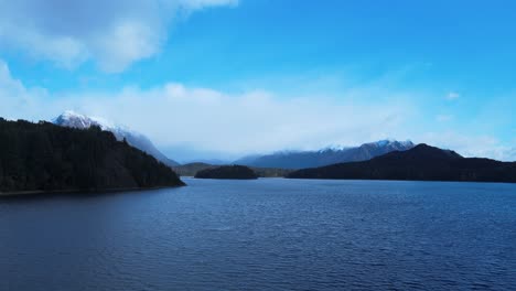 lake nahuel huapi on a sunny day between clouds, pronouncing winter with its white-topped mountains and a light wind bringing small waves to its darkened lake