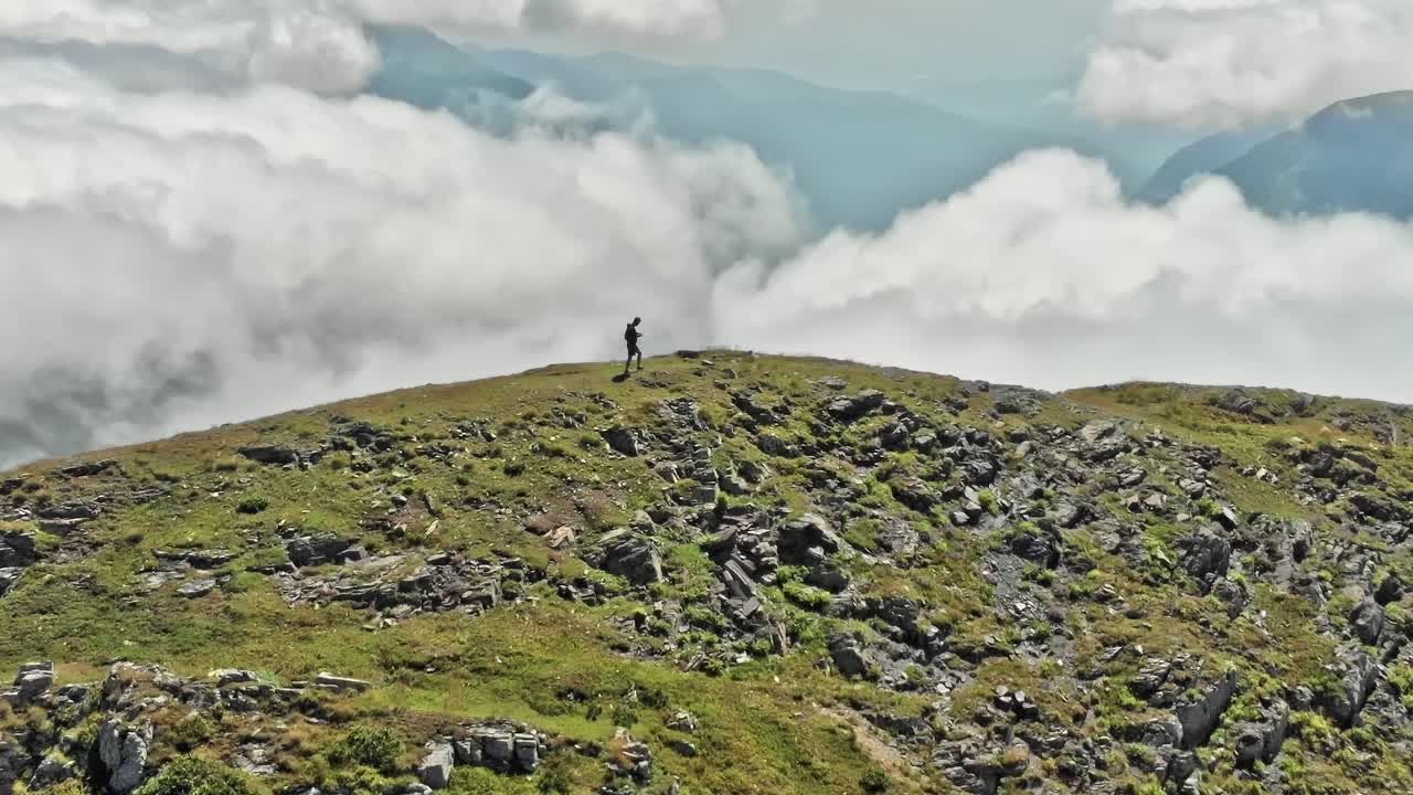 Un escursionista si erge su un crinale di montagna in Georgia, circondato dalle nuvole.