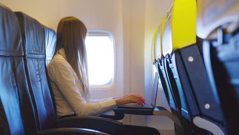 mujer trabajando en una computadora portátil en un avión