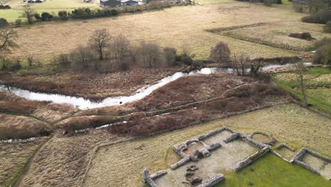 Ruinas-Del-Priorato-De-Castle-Acre-En-Southern-Park,-Norwich-Con-Pastizales-Circundantes-Y-Un-Río-Serpenteante,-Vista-Aérea