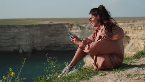 woman using phone on coastal cliff