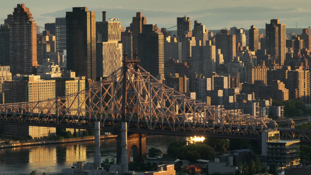Aerial view of the Queensboro Bridge at sunrise. Shot along the East River with Roosevelt Island and Manhattan in the background