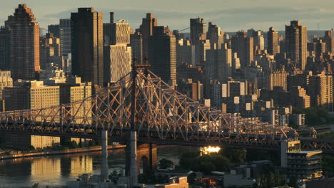 aerial view of the queensboro bridge at sunrise. shot along the east river with roosevelt island and manhattan in the background