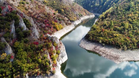 Aerial-drone-shot-pulling-away-over-river-Uvac-surrounded-by-gorgeous-rocky-tree-covered-cliffs,-slow-motion