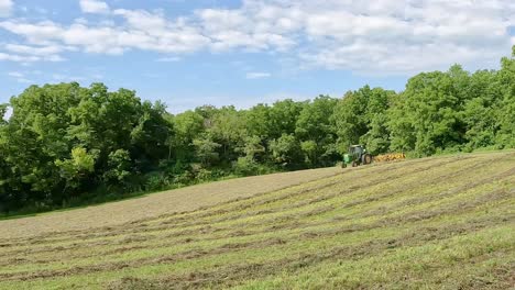 Grüner-Traktor,-Der-Sich-Am-Ende-Einer-Reihe-Dreht,-Um-Den-Heuharken-Neu-Auszurichten,-Um-Schwaden-In-Der-Geschnittenen-Und-Getrockneten-Luzerne-Zu-Bilden,-Um-Das-Heu-In-Ballen-Zu-Pressen